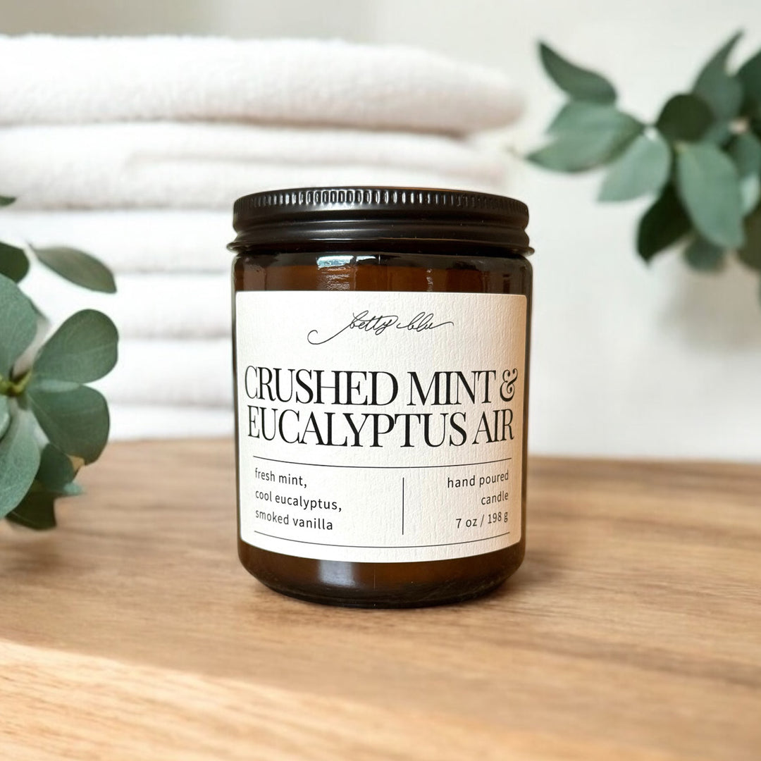 Amber jar candle with mint and eucalyptus label near folded towels.