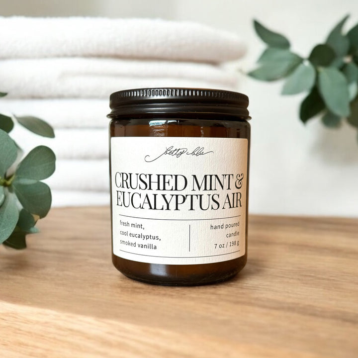 Amber jar candle with mint and eucalyptus label near folded towels.