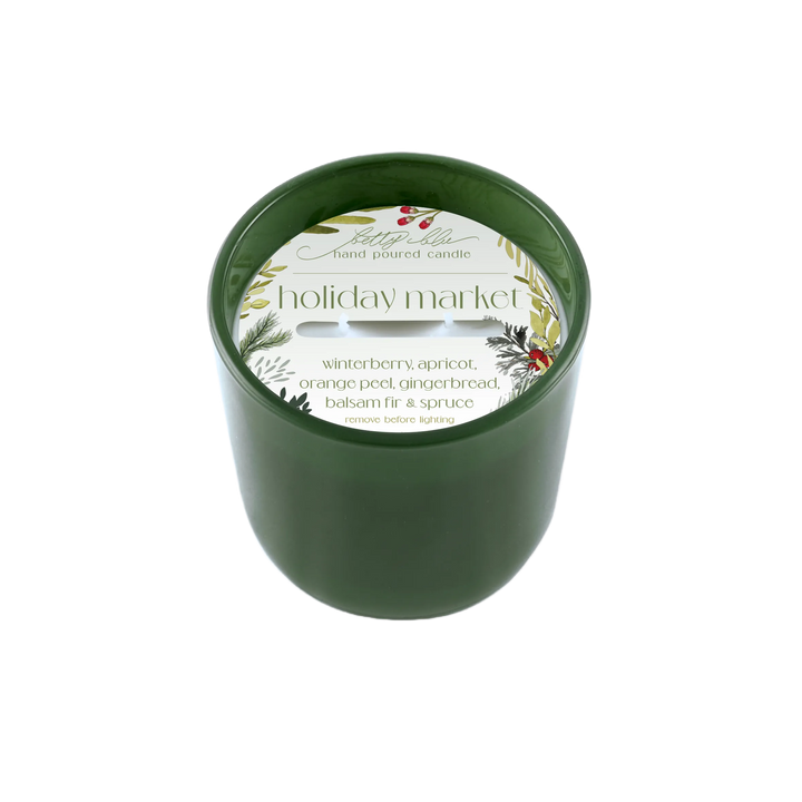 Forest green candle labeled “Holiday Market” with winter greenery and berries, hand-poured in the USA