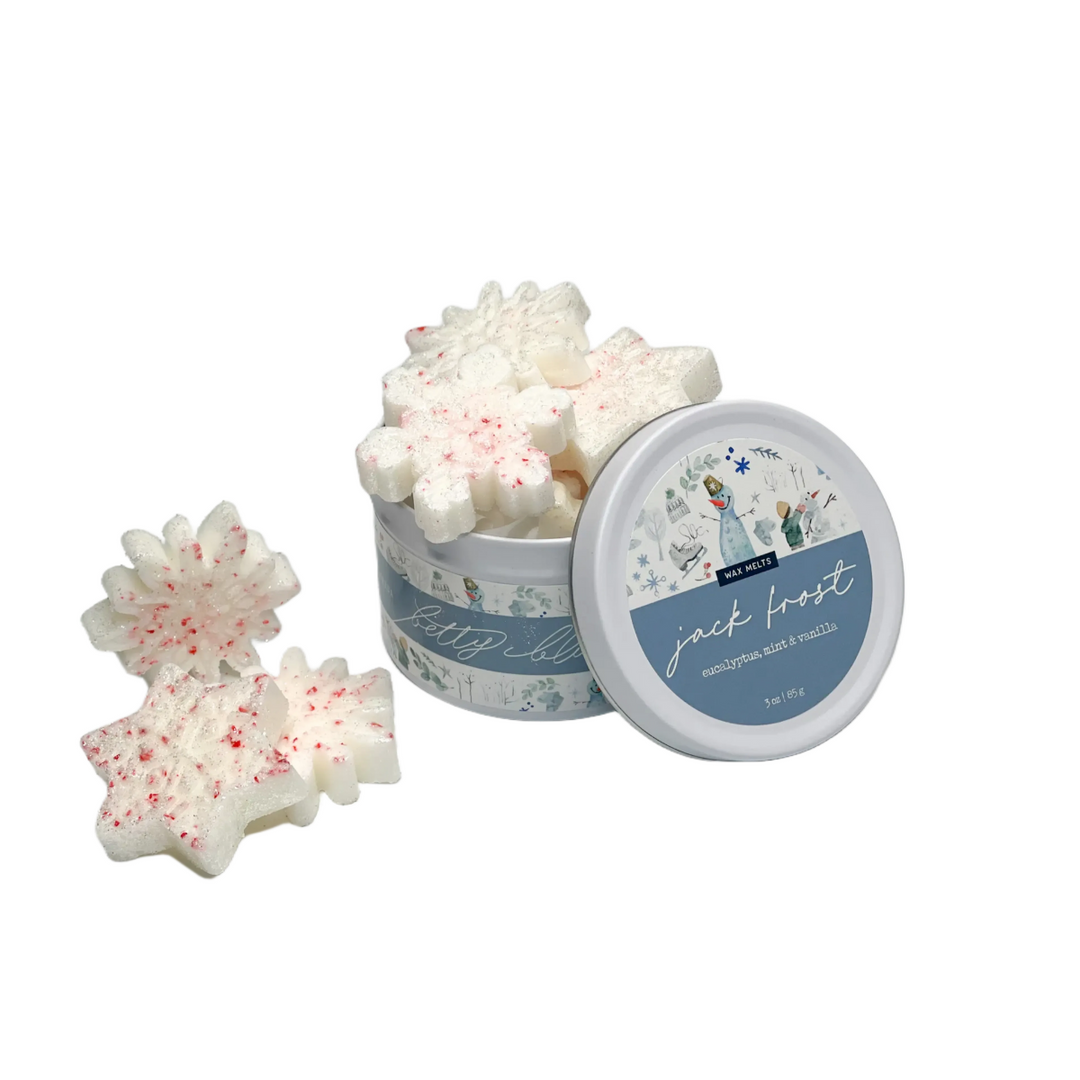 White snowflake wax melts with red flecks in a winter tin, scented with eucalyptus, mint, and vanilla