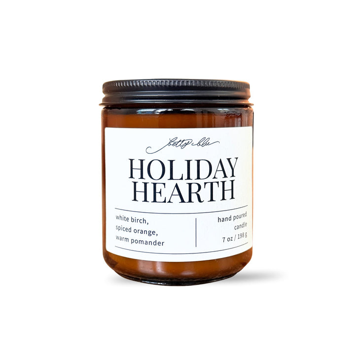 Holiday Hearth candle in amber glass jar with black lid.